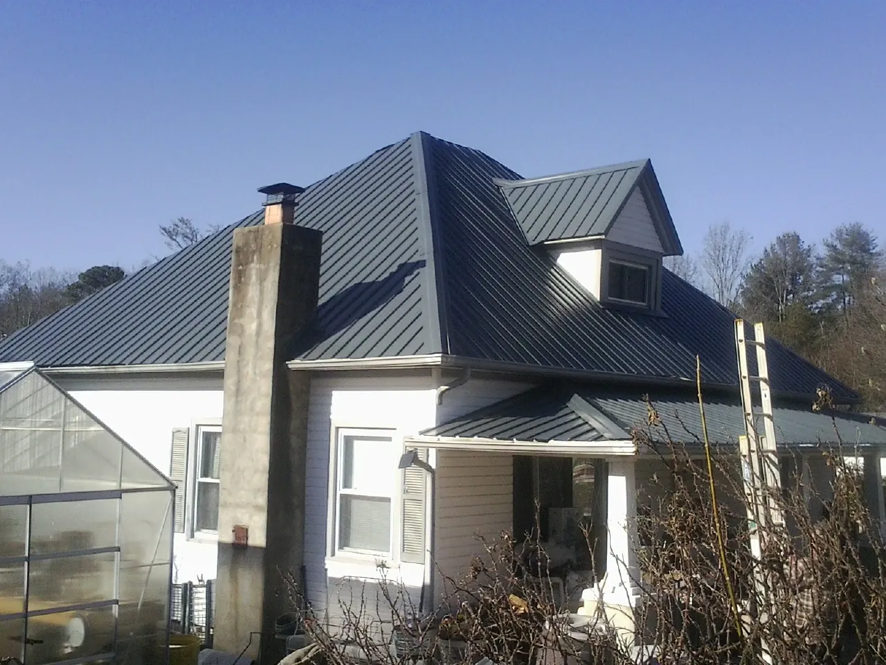 Dark blue standing seam metal roof on a white farmhouse with dormer — Slate & Tile Roof Repair by Roofing Brothers in Baldwin Place