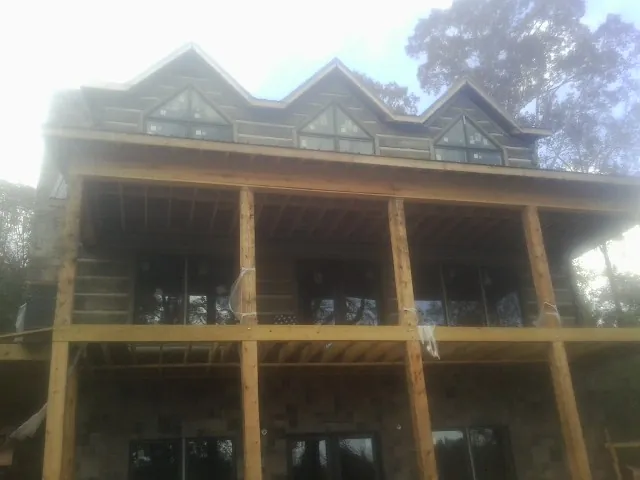 Dormers and porch framing on a large log home under construction — Roof Coating work by our crew in Baldwin Place