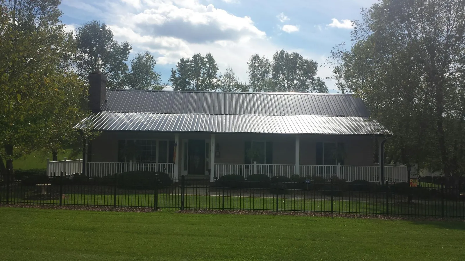 Gray metal roof on a brick ranch with a full width front porch — Gutter Guard Installation work by our crew in Baldwin Place