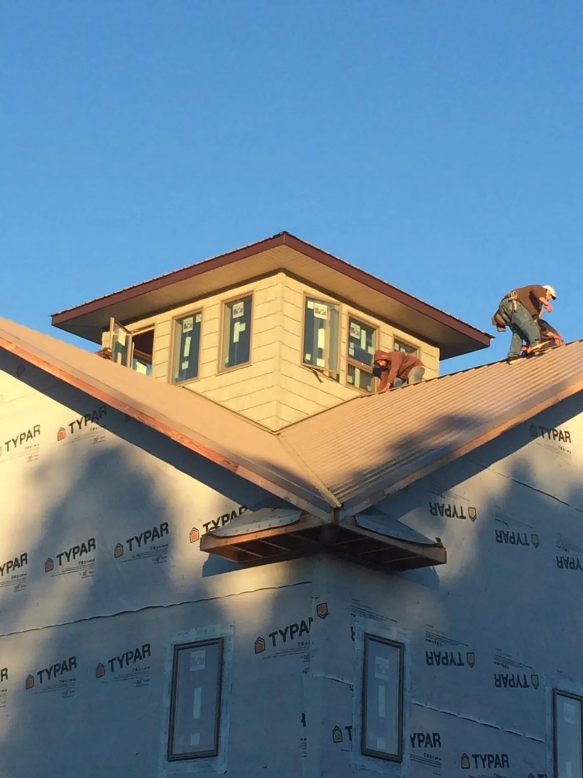 Roofers working around a rooftop cupola on a new metal roof at sunset — Roof Waterproofing in Baldwin Place by Roofing Brothers